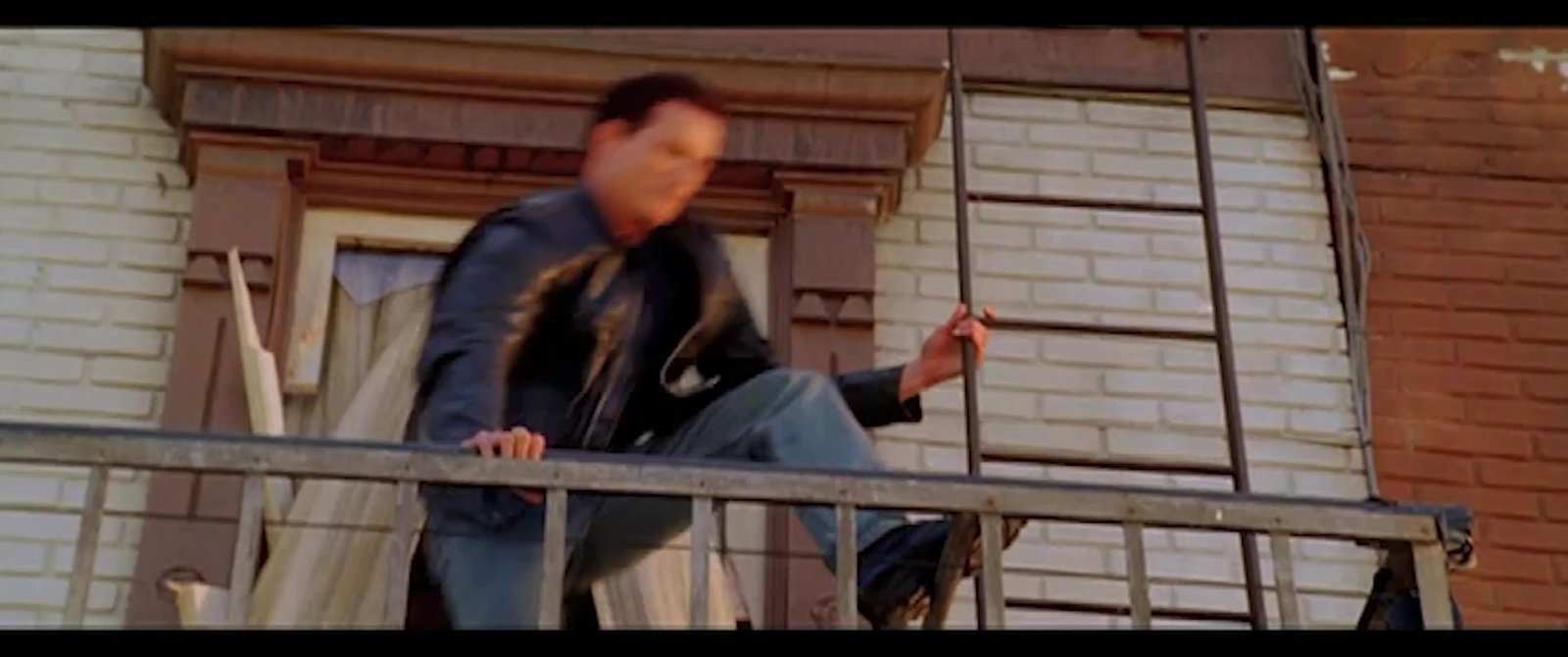 A man vaulting a fire-escape railing on a brick tenement
