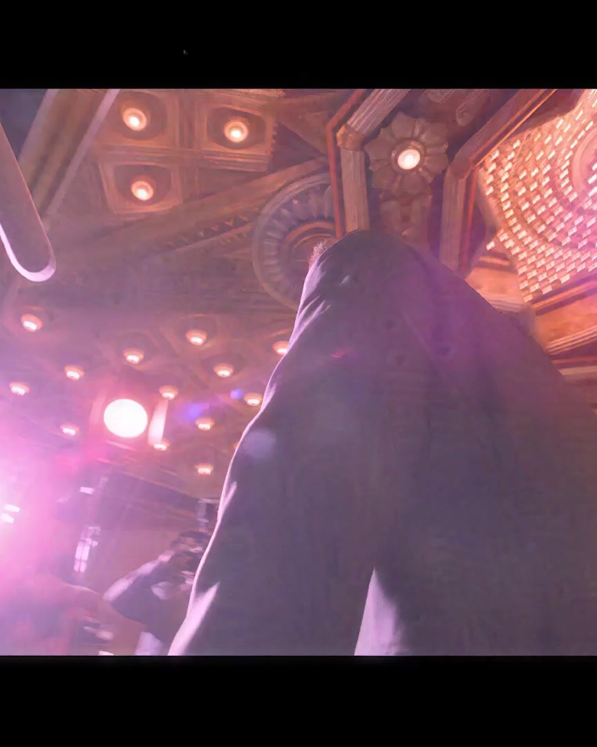 A bank of paparazzi camera flashes under an ornate theater marquee ceiling