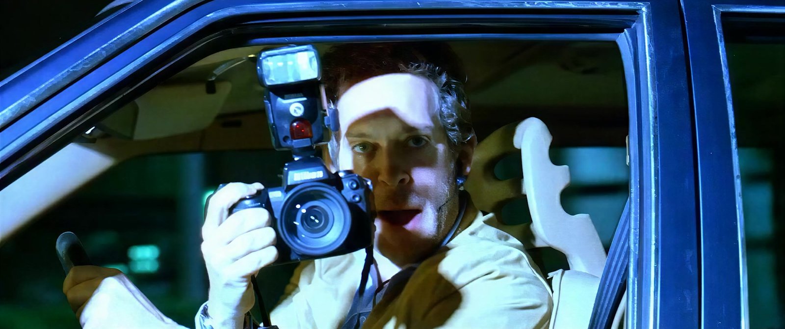 A bandaged paparazzo firing his camera from a car window